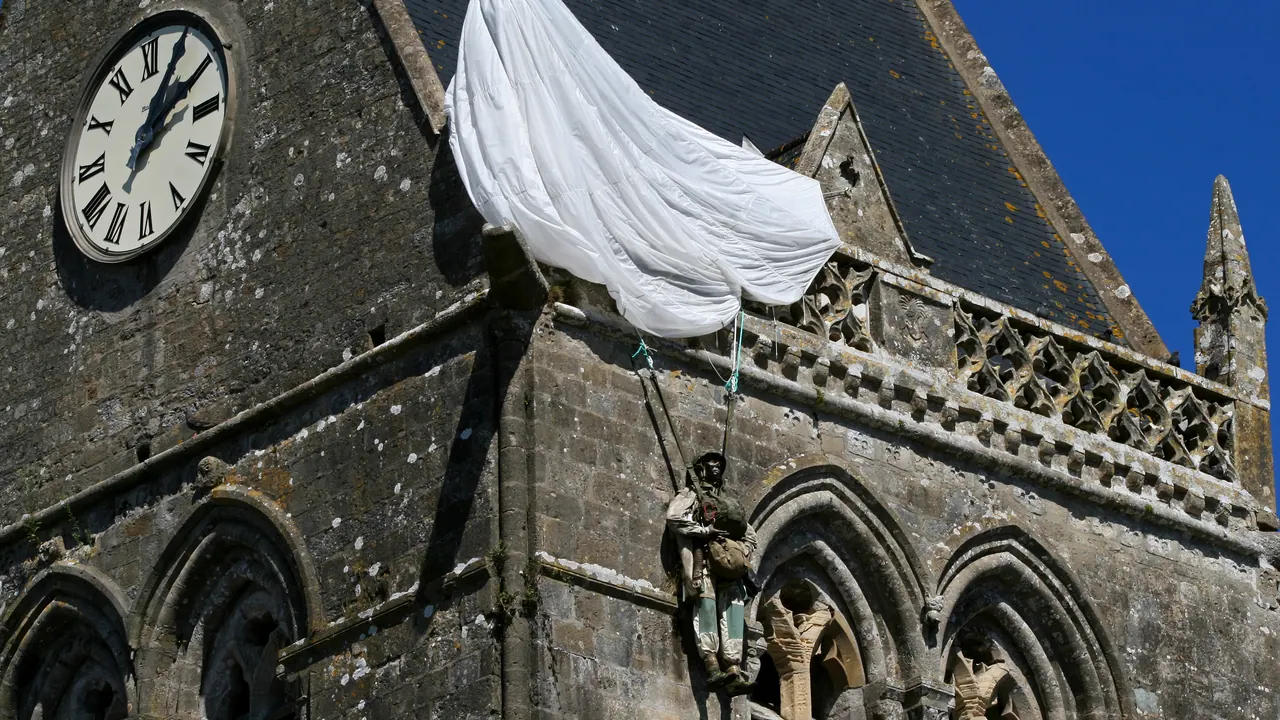 Parachute and paratrooper figure hanging from the bell tower of Sainte-Mère-Église church