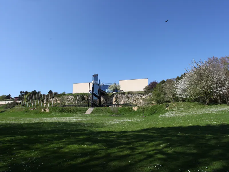 Lawn and flowering trees in the grounds of the Mémorial de Caen under blue sky