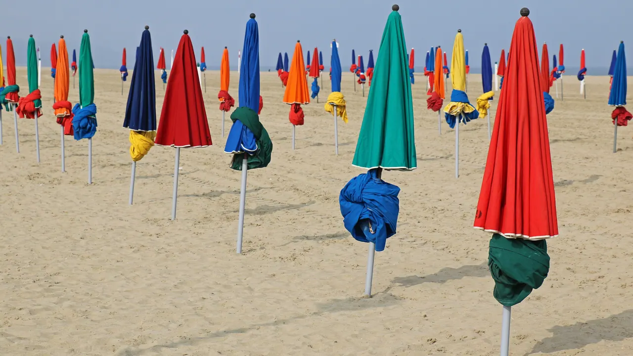 Rows of closed colourful parasols on the sand of Deauville beach