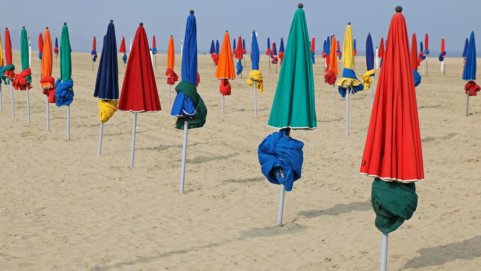 Rows of closed colourful parasols on the sand of Deauville beach
