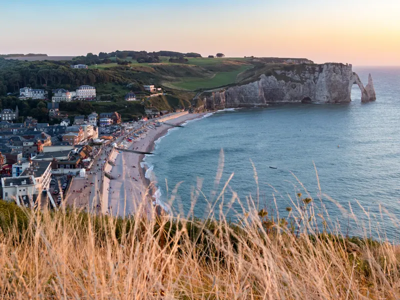 Étretat town, curved beach and Porte d'Aval cliffs seen from the eastern clifftop