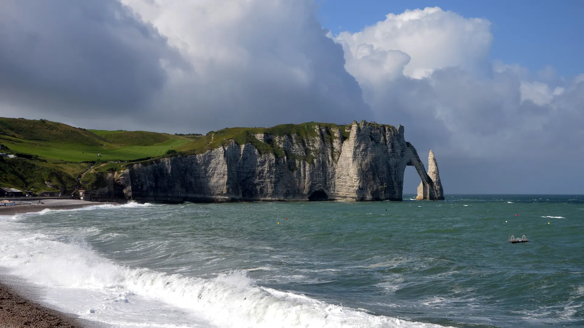 Étretat beach with waves breaking below the Porte d'Aval cliffs