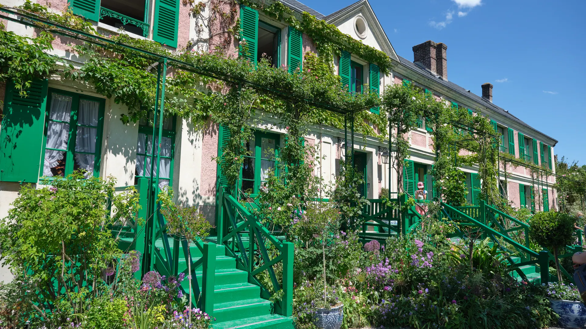 Claude Monet's pink house with green shutters and flower beds in Giverny