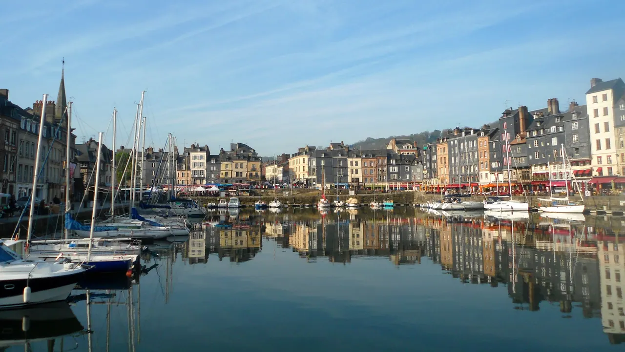 Tall narrow houses and moored sailboats reflected in Honfleur's Vieux Bassin harbour