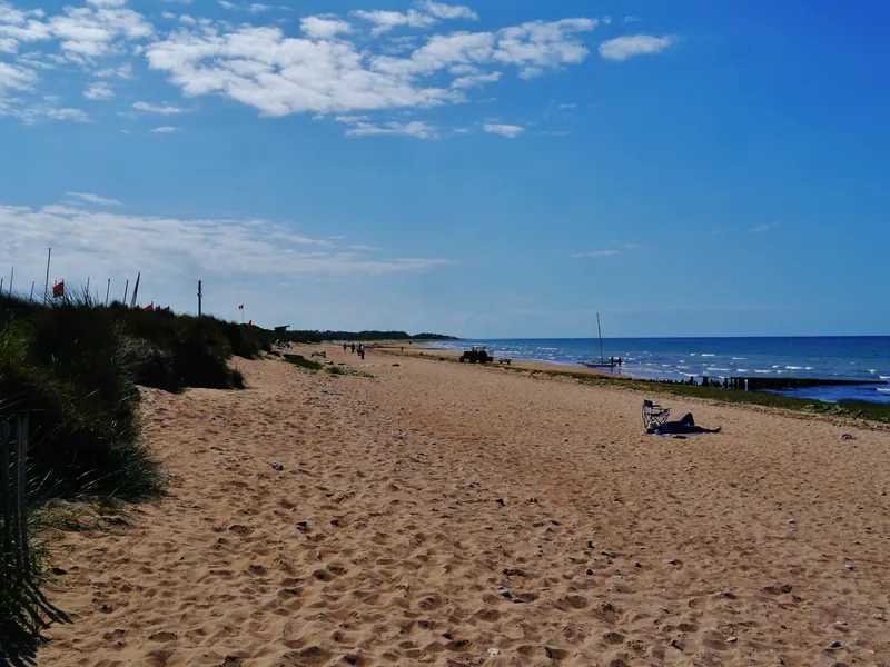 Sandy Juno Beach at Courseulles-sur-Mer with dune grass and a calm blue sea