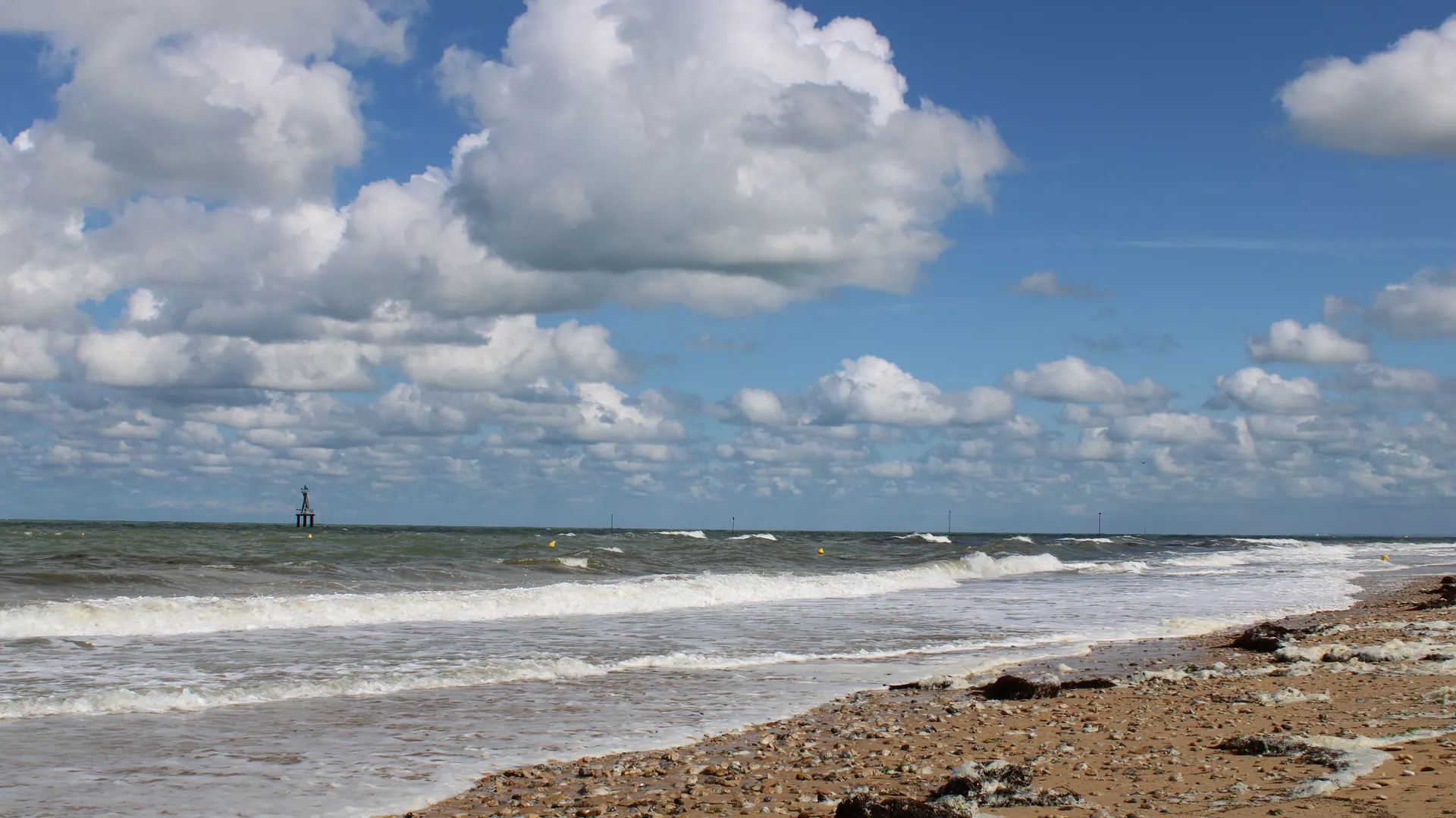 Juno Beach shoreline at Courseulles-sur-Mer with waves and scattered clouds