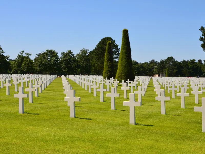 White crosses in long rows among trees at the American cemetery in Colleville-sur-Mer