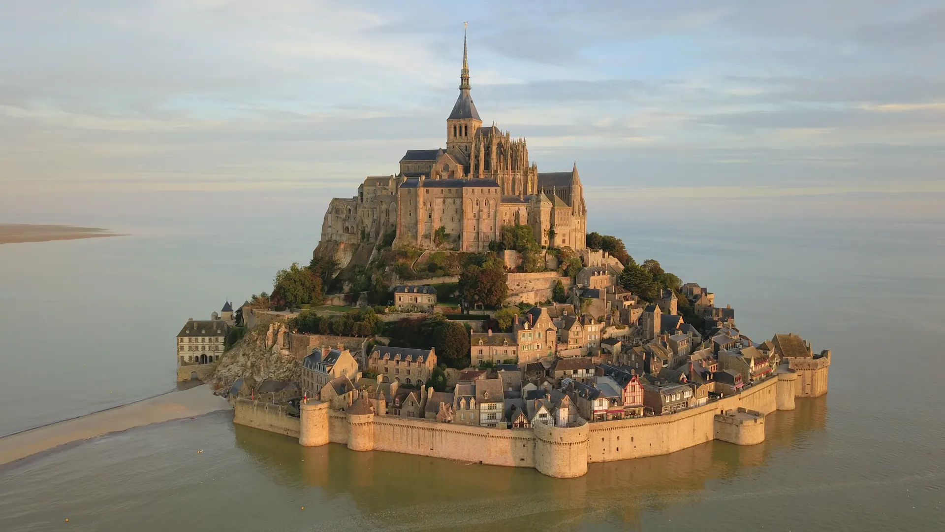 Aerial view of Mont-Saint-Michel surrounded by water at sunrise during high tide